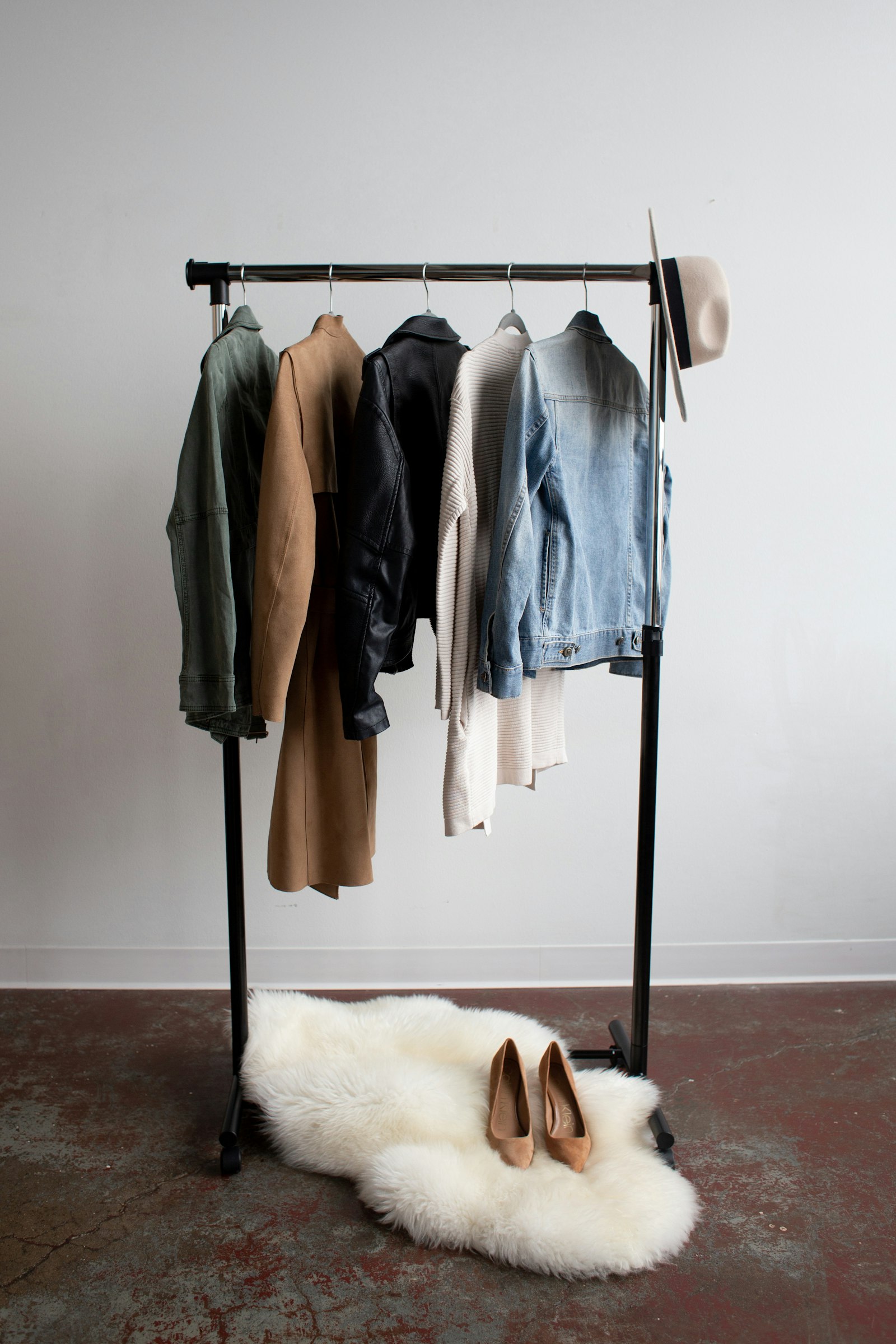 Five neutral-toned jackets hanging on a simple clothes rack