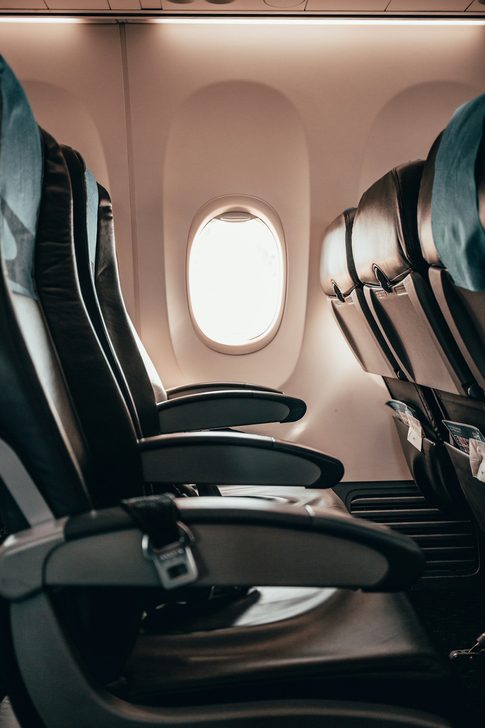 View down an airplane economy aisle showing seats and underseat space